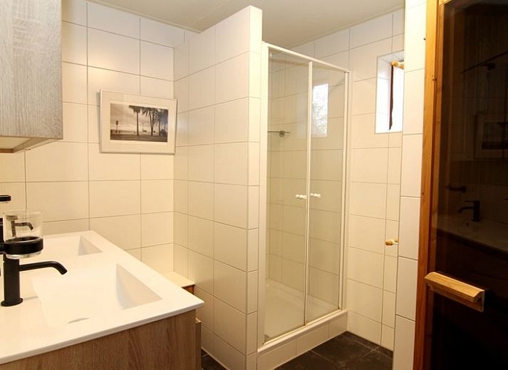 Vakantiehuis F 455 in De Cocksdorp, Texel biedt een charmant terras met comfortabele zithoek en parasol, omgeven door groene natuur.