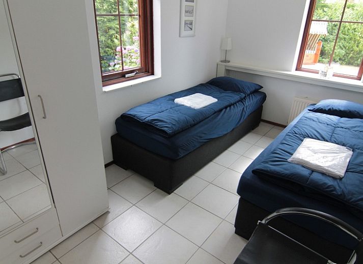 Vakantiehuis E 638 in De Cocksdorp, Texel, omgeven door bloeiende rozenstruiken en een zonnige tuin, ideaal voor een ontspannen verblijf.