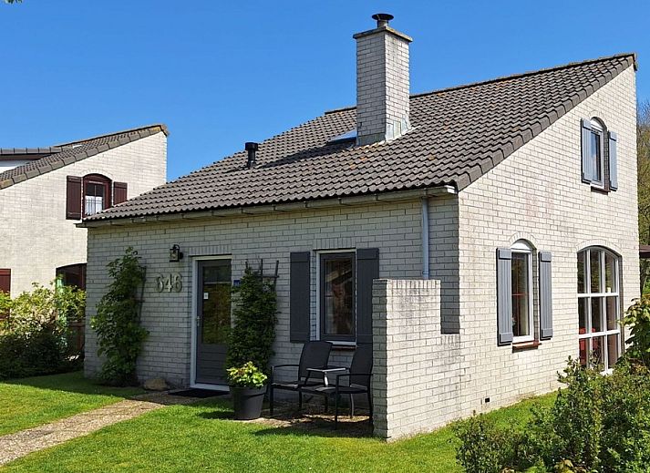 Vakantiehuis E 646 in De Cocksdorp, Texel biedt een charmante buitenruimte met groene tuin en comfortabele zitplek, ideaal voor ontspanning.