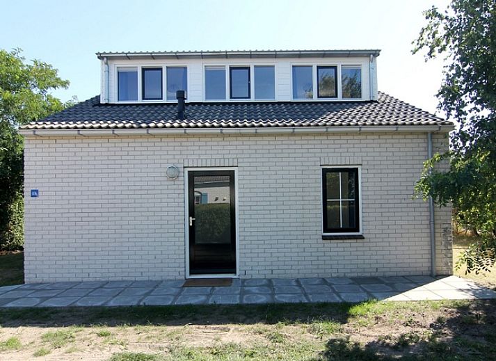 Geniet van de zon op het terras van Vakantiehuis E 614 in De Cocksdorp, Texel, met comfortabele ligstoelen en een parasol voor ontspanning.