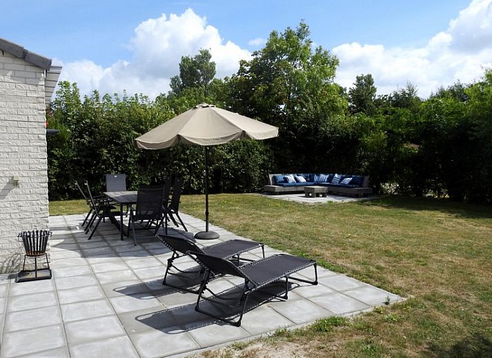 Geniet van de zon op het terras van Vakantiehuis E 614 in De Cocksdorp, Texel, met comfortabele ligstoelen en een parasol voor ontspanning.