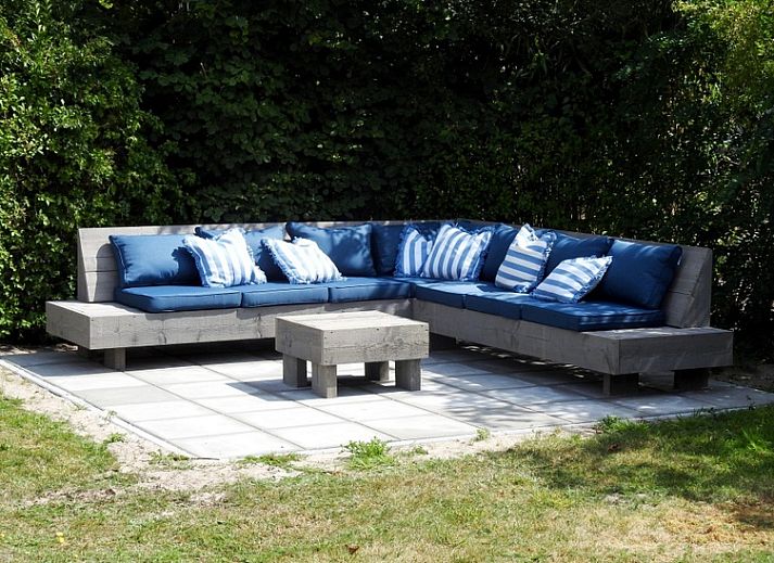 Geniet van de zon op het terras van Vakantiehuis E 614 in De Cocksdorp, Texel, met comfortabele ligstoelen en een parasol voor ontspanning.