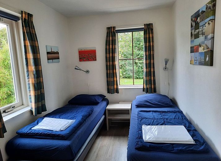 Vakantiehuis E 409 in De Cocksdorp, Texel biedt een charmante buitenkant met een uitnodigend terras en groene omgeving.