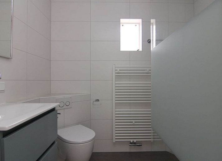 Vakantiehuis E 409 in De Cocksdorp, Texel biedt een charmante buitenkant met een uitnodigend terras en groene omgeving.