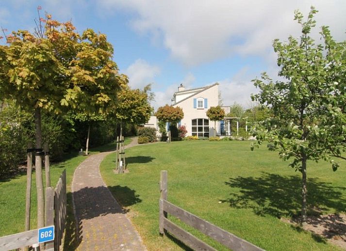 Vakantiehuis F 602 in De Cocksdorp, Texel, omgeven door groene natuur en een uitnodigend pad naar de voordeur van deze charmante vakantiewoning.