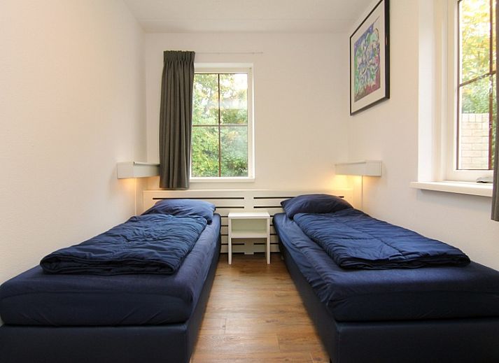 Vakantiehuis E 421 in De Cocksdorp, Texel, biedt een charmante verblijfservaring met een uitnodigende voorgevel en groene omgeving.