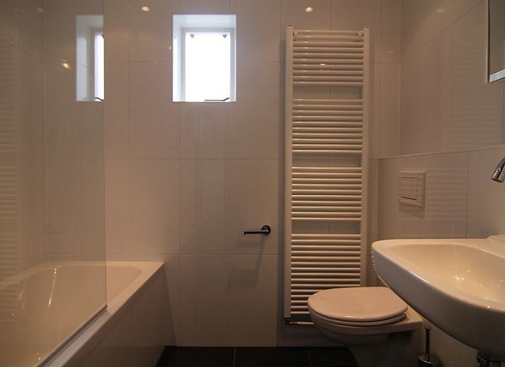 Vakantiehuis E 421 in De Cocksdorp, Texel, biedt een charmante verblijfservaring met een uitnodigende voorgevel en groene omgeving.