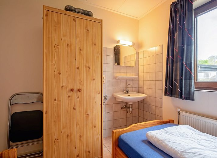 Gezellige woonkamer van Vakantiehuis Slufterhoek 110 in De Cocksdorp, Texel met uitzicht op groene tuin en comfortabele zithoek.