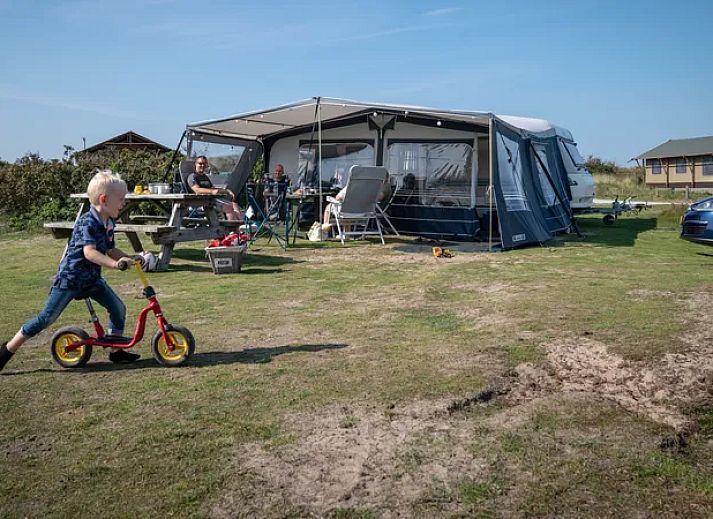 Kind speelt op gras bij Sluftervallei Comfort campingplaats C3 in De Cocksdorp, Texel.