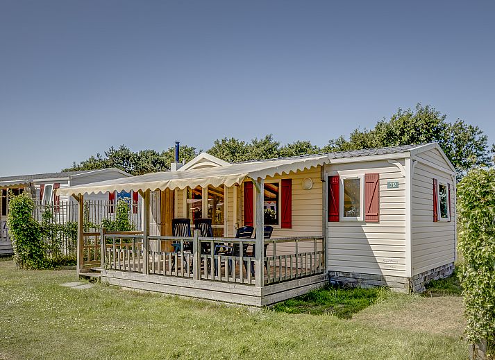 Zonnige veranda van Sluftervallei 4-persoons stacaravan 4MH in De Cocksdorp, Texel, omgeven door groen.