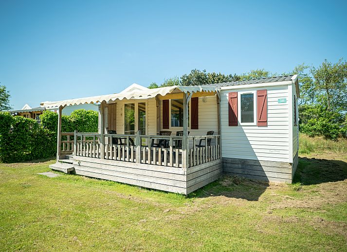 Zonnige veranda van Sluftervallei 4-persoons stacaravan 4MH in De Cocksdorp, Texel, omgeven door groen.