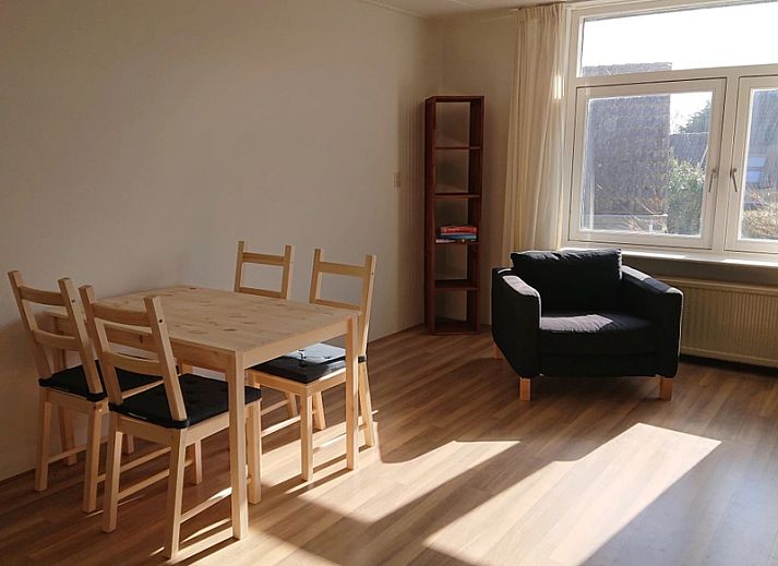 Helles Interieur des Ferienhauses Kikkerpoel in De Cocksdorp, Texel mit Holzboden und bequemem Sessel.