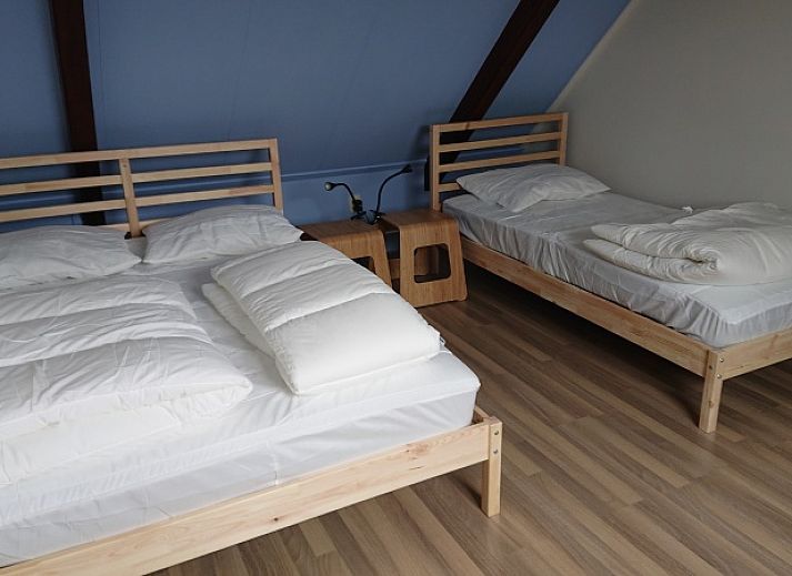 Helles Interieur des Ferienhauses Kikkerpoel in De Cocksdorp, Texel mit Holzboden und bequemem Sessel.