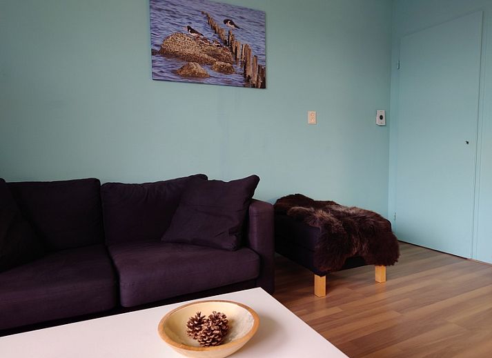 Gemuetliche Essecke im Ferienhaus Kikkerpoel, De Cocksdorp, Texel mit Holztisch und Stuehlen am grossen Fenster.