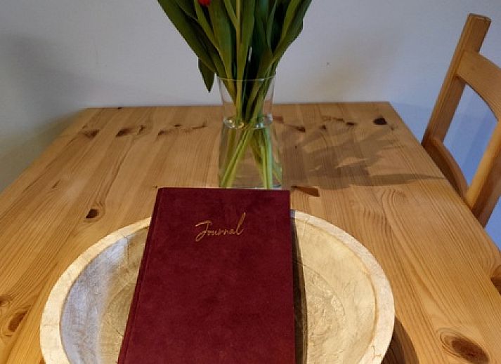 Gemuetliche Essecke im Ferienhaus Kikkerpoel, De Cocksdorp, Texel mit Holztisch und Stuehlen am grossen Fenster.