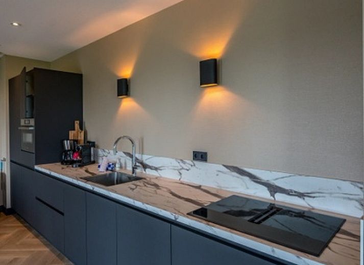 Avondzicht op 6 persoons vakantiewoning in De Cocksdorp, Texel met sfeervolle verlichting en moderne inrichting.