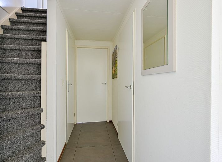 Gerumiges Wohnzimmer eines freistehenden Hauses in De Koog, Texel, mit moderner Einrichtung und viel natrlichem Licht durch die groen Fenster.