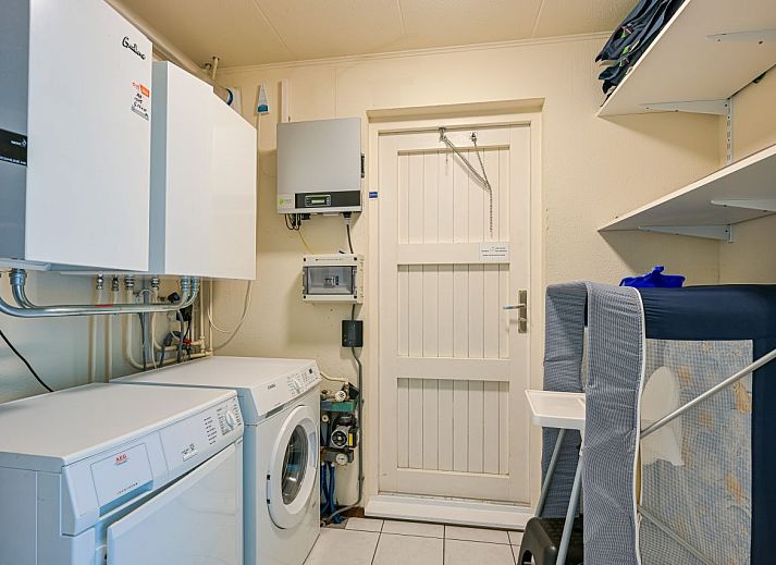 Gerumiges Wohnzimmer eines freistehenden Hauses in De Koog, Texel, mit moderner Einrichtung und viel natrlichem Licht durch die groen Fenster.