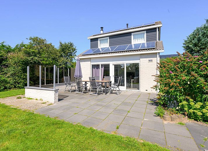 Gerumiges Wohnzimmer eines freistehenden Hauses in De Koog, Texel, mit moderner Einrichtung und viel natrlichem Licht durch die groen Fenster.