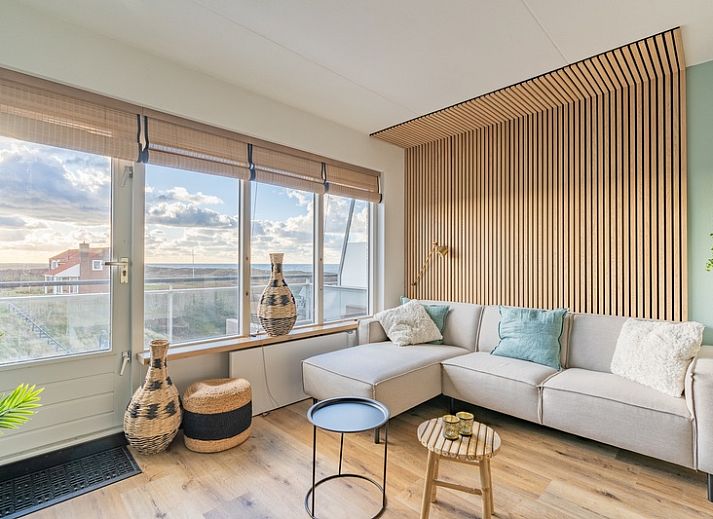 Appartement Juliana 140 Eiland en Zeezicht in De Koog, Texel biedt een sfeervolle woonkamer met uitzicht op de duinen.