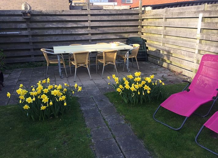 Backyard of The Duinputter vacation home in De Koog Texel with balcony and green surroundings.