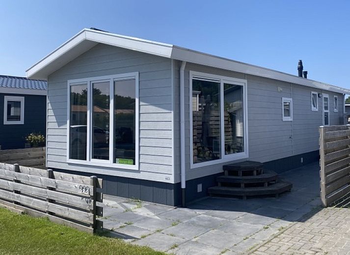 Chalet Bregkoog 232 in De Koog, Texel, met houten omheining en grote ramen, ideaal vakantiehuis op de Waddeneilanden.