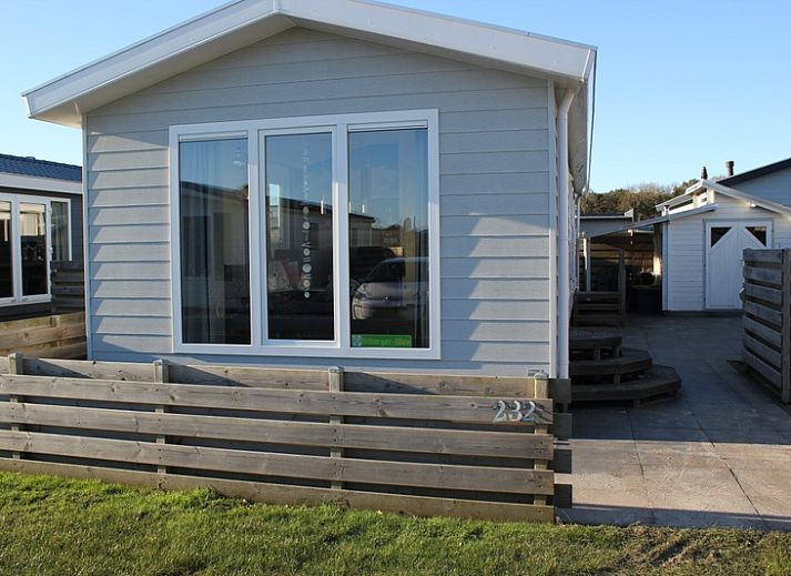 Chalet Bregkoog 232 in De Koog, Texel, met houten omheining en grote ramen, ideaal vakantiehuis op de Waddeneilanden.