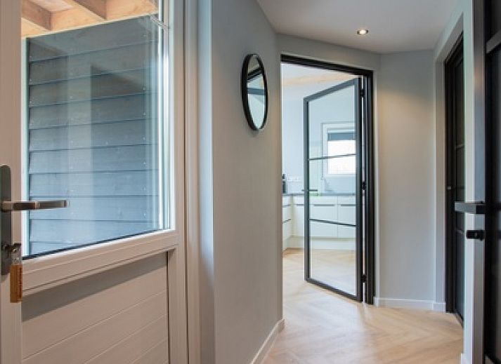 Stijlvolle woonkamer in De Houtsnip vakantiehuis, De Koog, Texel met hoge plafonds en comfortabele zithoek.