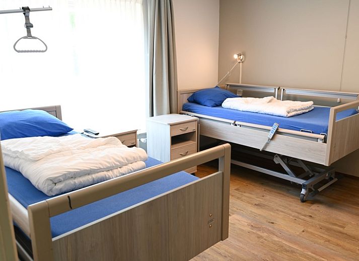 Vooraanzicht van Tesselhuus met zorgvleugel, vakantiehuis in De Koog, Texel, met parkeerplaats en groene omgeving.