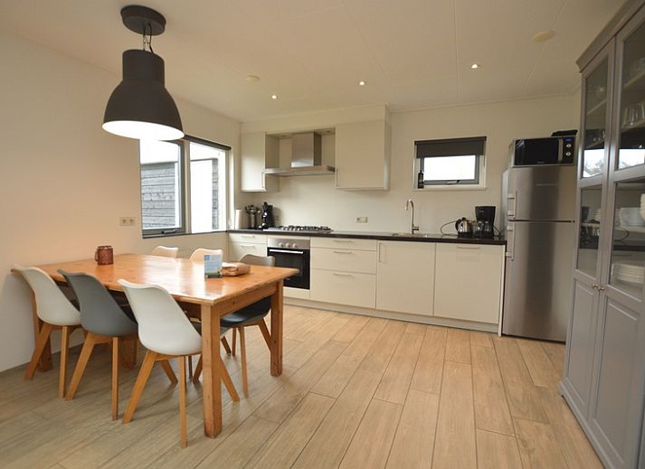 Gemuetliches Wohnzimmer des Ferienhauses Stappeland 215 in De Koog, Texel, mit bequemer Sitzecke und Gartenblick.