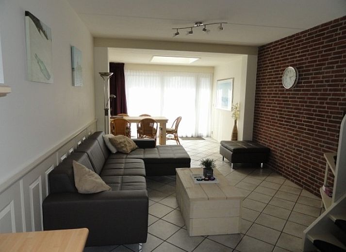 Gezellig terras bij Vakantiehuis Koogerduin in De Koog, Texel, met houten tafel en kleurrijke bloemen.