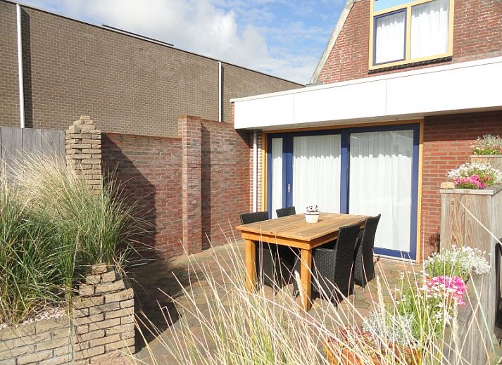 Gezellig terras bij Vakantiehuis Koogerduin in De Koog, Texel, met houten tafel en kleurrijke bloemen.