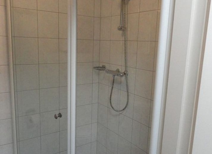 Gezellig terras bij Vakantiehuis Koogerduin in De Koog, Texel, met houten tafel en kleurrijke bloemen.