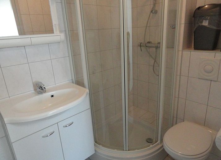 Gezellig terras bij Vakantiehuis Koogerduin in De Koog, Texel, met houten tafel en kleurrijke bloemen.