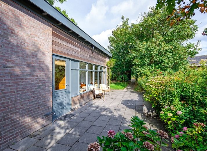 De Zonneweelde vakantiehuis in De Koog, Texel omgeven door groene natuur en zonlicht.