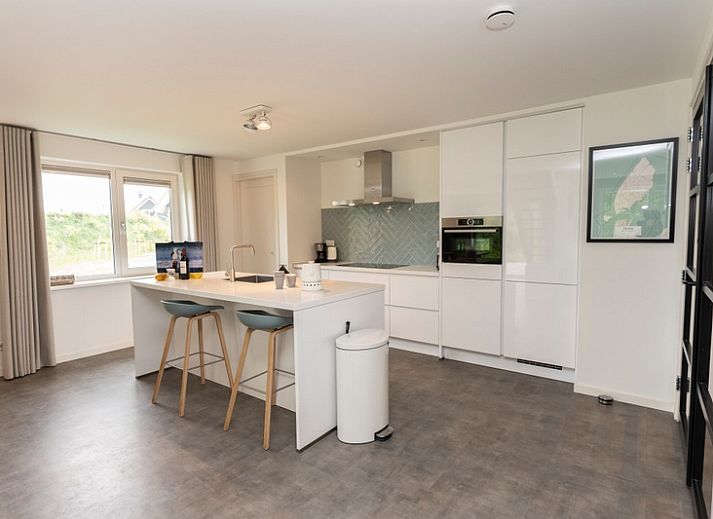 Moderne eetkamer in Buitenduin vakantiehuis, De Koog, Texel met houten tafel en open keuken.