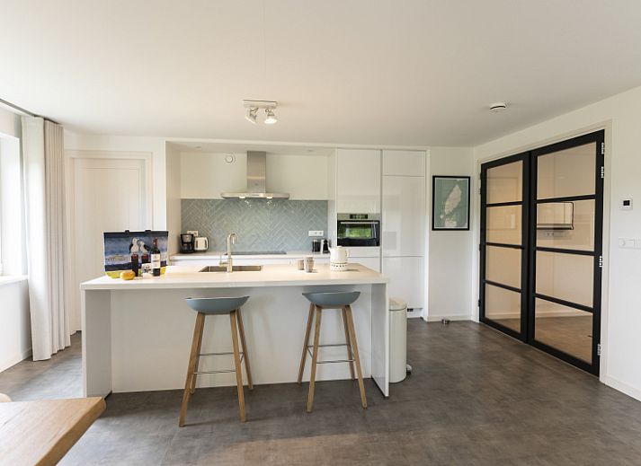 Moderne eetkamer in Buitenduin vakantiehuis, De Koog, Texel met houten tafel en open keuken.