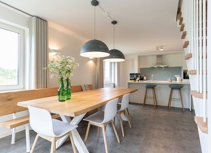 Moderne eetkamer in Buitenduin vakantiehuis, De Koog, Texel met houten tafel en open keuken.