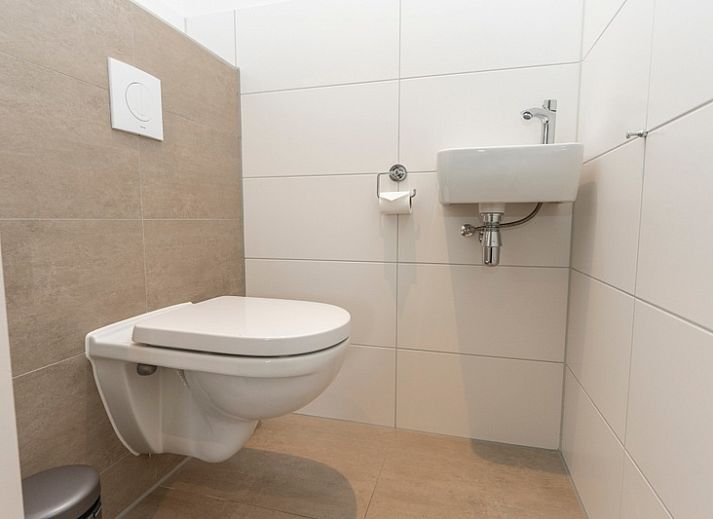 Moderne eetkamer in Buitenduin vakantiehuis, De Koog, Texel met houten tafel en open keuken.