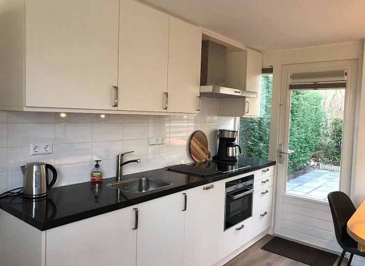 't Buitenhuisje in De Koog, Texel biedt een moderne woonkamer met comfortabele stoelen en een gezellige sfeer in dit vakantiehuis.