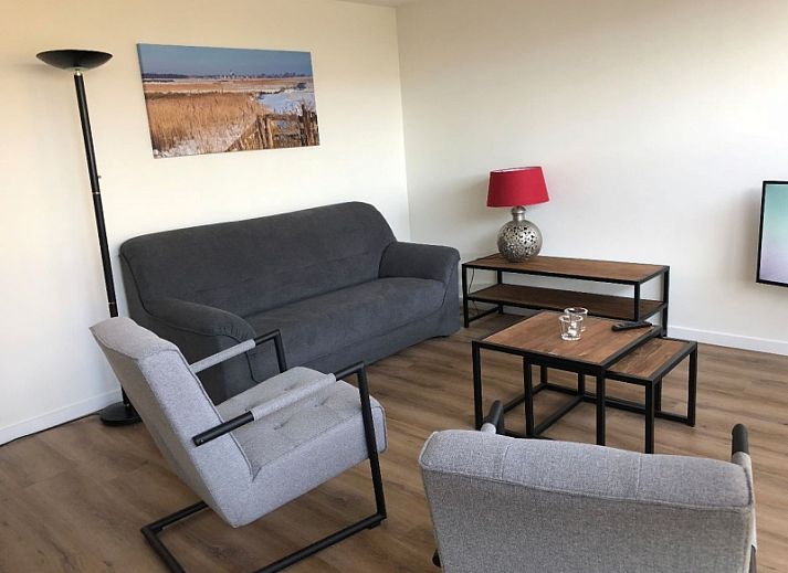 't Buitenhuisje in De Koog, Texel biedt een moderne woonkamer met comfortabele stoelen en een gezellige sfeer in dit vakantiehuis.