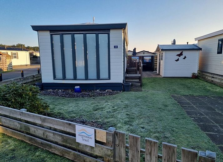 Chaletpark Bregkoog - Chalet Bregkoog 33 in De Koog, Texel met charmante tuin en houten hek, ideaal voor een ontspannen vakantie.