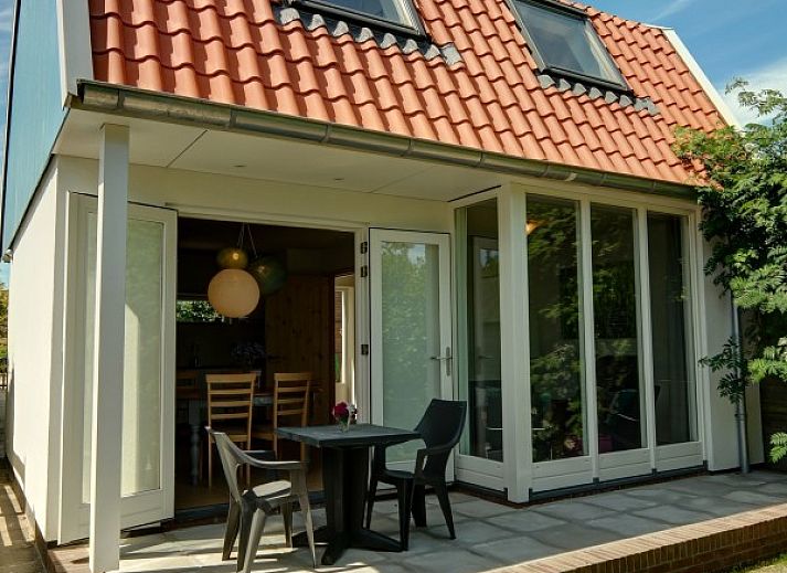 Knusse zithoek in vakantiehuis Zusje van 17, De Koog, Texel met comfortabele stoelen en tuinzicht.