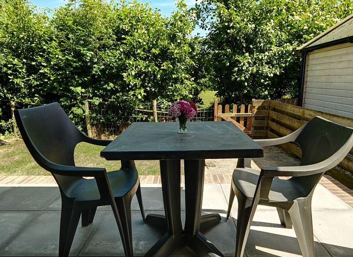 Knusse zithoek in vakantiehuis Zusje van 17, De Koog, Texel met comfortabele stoelen en tuinzicht.