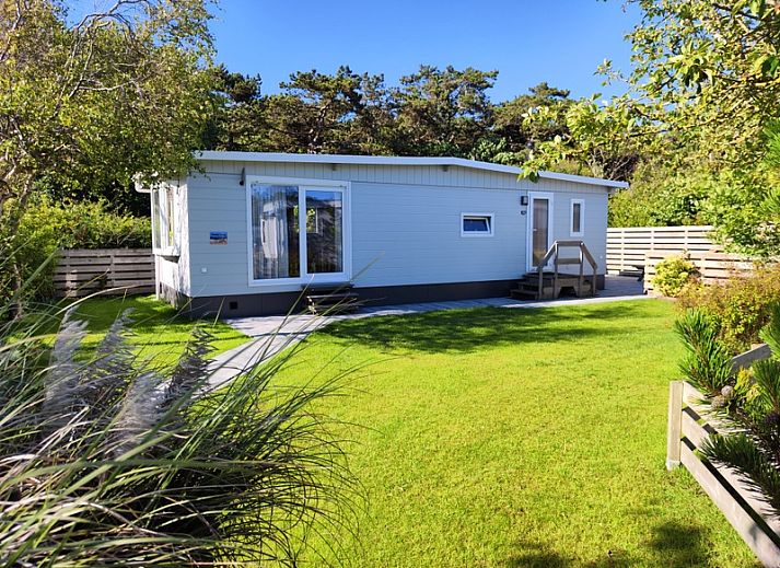 Chalet Bregkoog 207 in De Koog, Texel met een groene tuin en bomen.