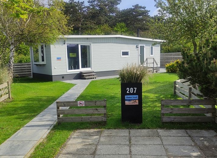 Chalet Bregkoog 207 in De Koog, Texel met een groene tuin en bomen.
