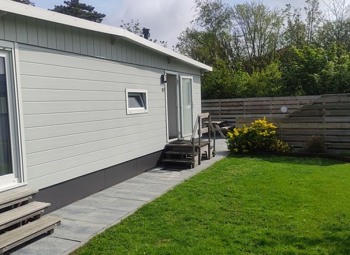 Chalet Bregkoog 207 in De Koog, Texel met een groene tuin en bomen.