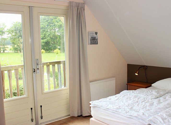 Moderne Kueche im reetgedeckten 6-Personen-Ferienhaus Eldorado Texel, De Koog, mit Essecke und Blick auf die gruene Umgebung der Waddeninseln.
