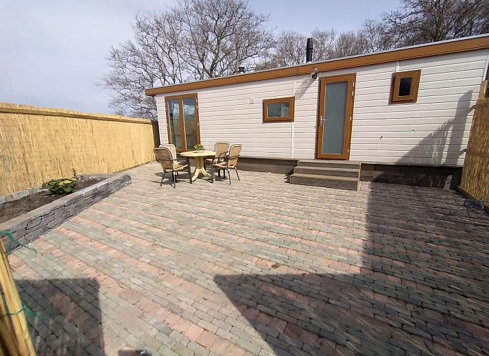 Moderne woonkamer van Chalet Uit en Thuis, Texel, met uitzicht op de tuin en comfortabele stoelen.