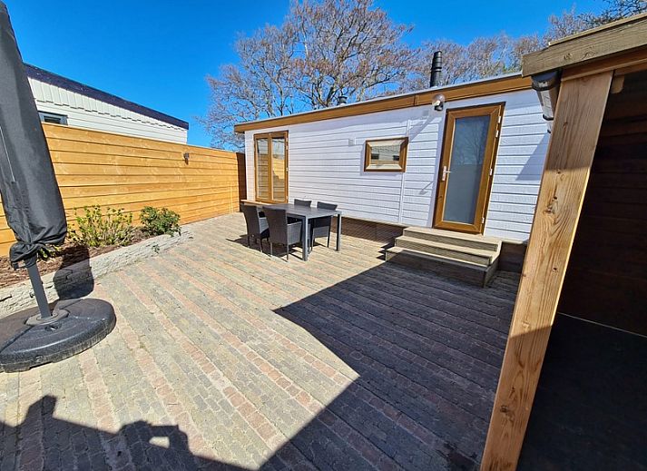 Moderne woonkamer van Chalet Uit en Thuis, Texel, met uitzicht op de tuin en comfortabele stoelen.